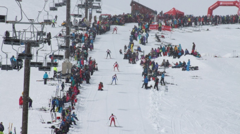 Dalībnieki, līdzjutēju atbalstīti, tuvojas finišam distanču slēpošanas daļā. Foto:no organizētāju mājaslapas.