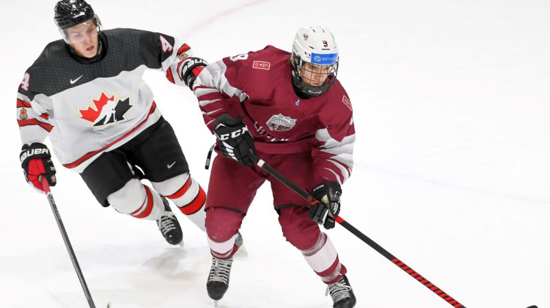 Aizsargs Kristers Doniņš (Nr. 4) pret kanādieti Hadsonu Malinoski. Foto: Robert Levebvre/Hockey Canada Images